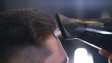 barber drying male hair in hairdressing salon. close up hairdresser blowing man hair with dryer in barbershop. male hairstylish doing hairdo in beauty studio