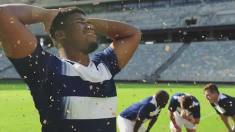 Animation-of-confetti-falling-over-african-american-male-rugby-player-at-stadium