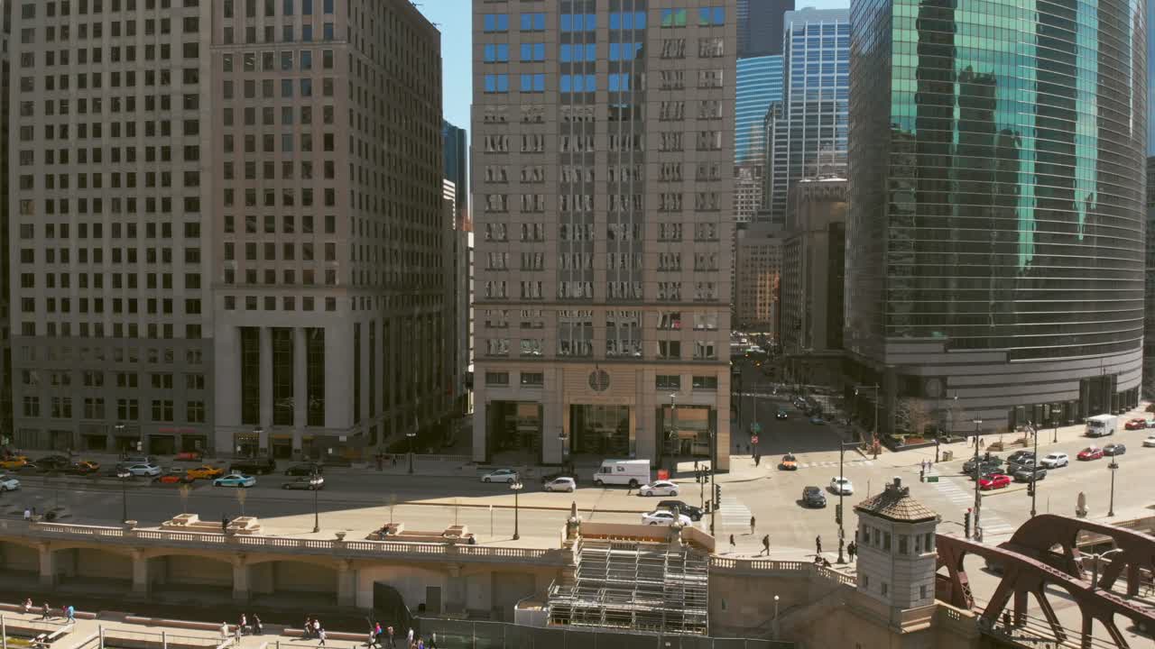 Ampia ripresa aerea del centro di Chicago lungo il fiume, mentre il drone esegue una carrellata aerea fluida, rivelando ponti, pedoni e grattacieli circostanti