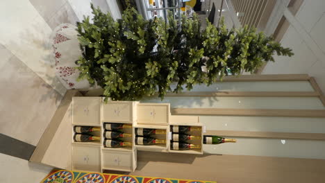 video vertical con árbol de navidad y botellas de vino exhibidas en un centro comercial