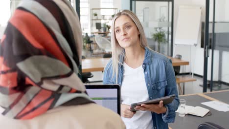 busy diverse businesswomen discussing work with laptop and tablet in office in slow motion