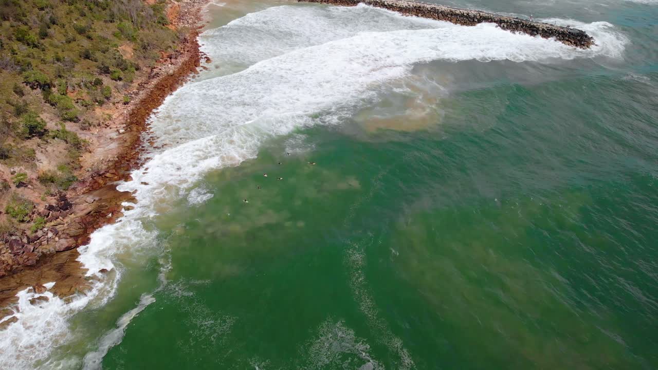 vista aérea sobre las olas golpeando la costa de la ciudad principal de evans, día soleado - inclinación hacia arriba, disparo de drones