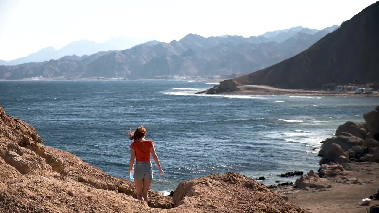 chica caminando desde el mirador mirando el agujero azul en dahab en el mar rojo en egipto
