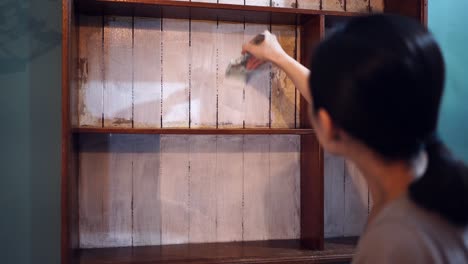 asian woman painting wooden shelves at home