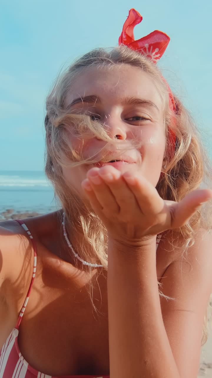 Young joy caucasian woman takes selfie on phone and sends air kiss from beach
