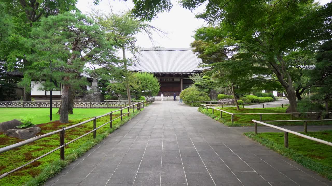 The entrances to many Buddhist temples in Japan are long passageways through their beautiful gardens ending at the main building. Fast motion.