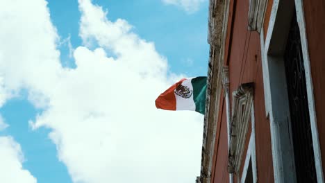 In-Zeitlupe-Wurde-Die-Mexikanische-Flagge-Aufgenommen,-Die-Anmutig-Auf-Einem-Gebäude-Weht-Und-Nationalstolz-Und-Erbe-Symbolisiert