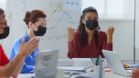 Mujer-De-Negocios-Intercambiando-Ideas-Con-Colegas.-Gente-Enmascarada-Sentado-Mesa-Oficina