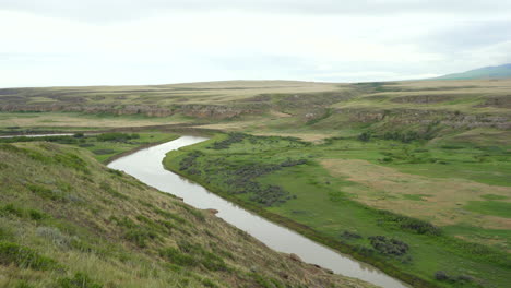 Writing-on-Stone-Provincial-Parks-bandlands-and-Hoodoos-in-a-desert-in-Alberta,-Canada-during-overcast-day-with-river-at-a-distance