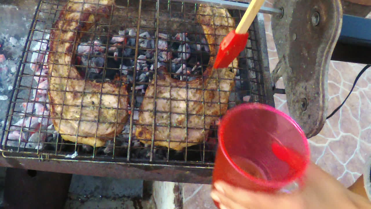 야외 바비큐에서 두 개의 거대한 돼지 갈비를 담그는 여성 요리사