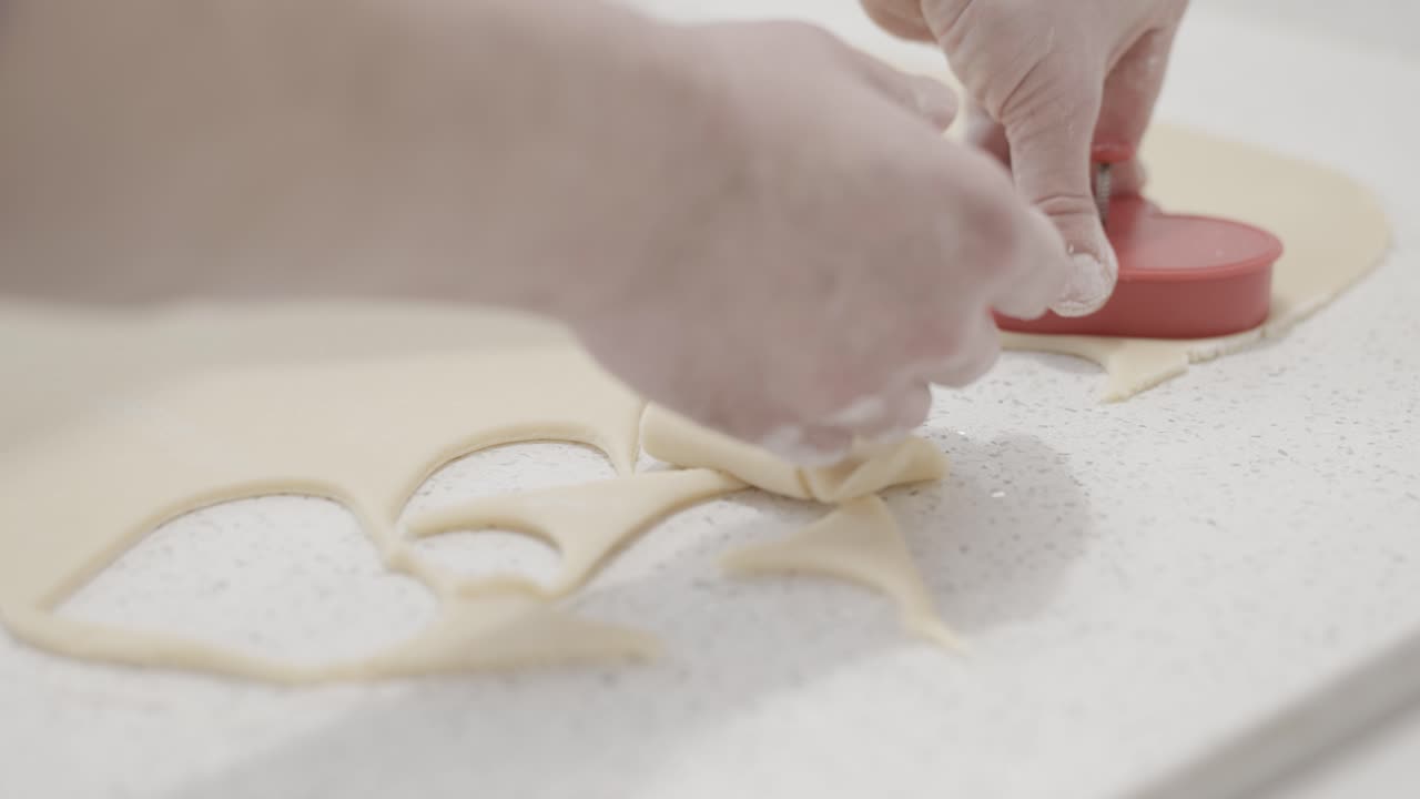 cortando galletas de mantequilla en forma de corazón en una pastelería usando un cortador de galletas, 4k