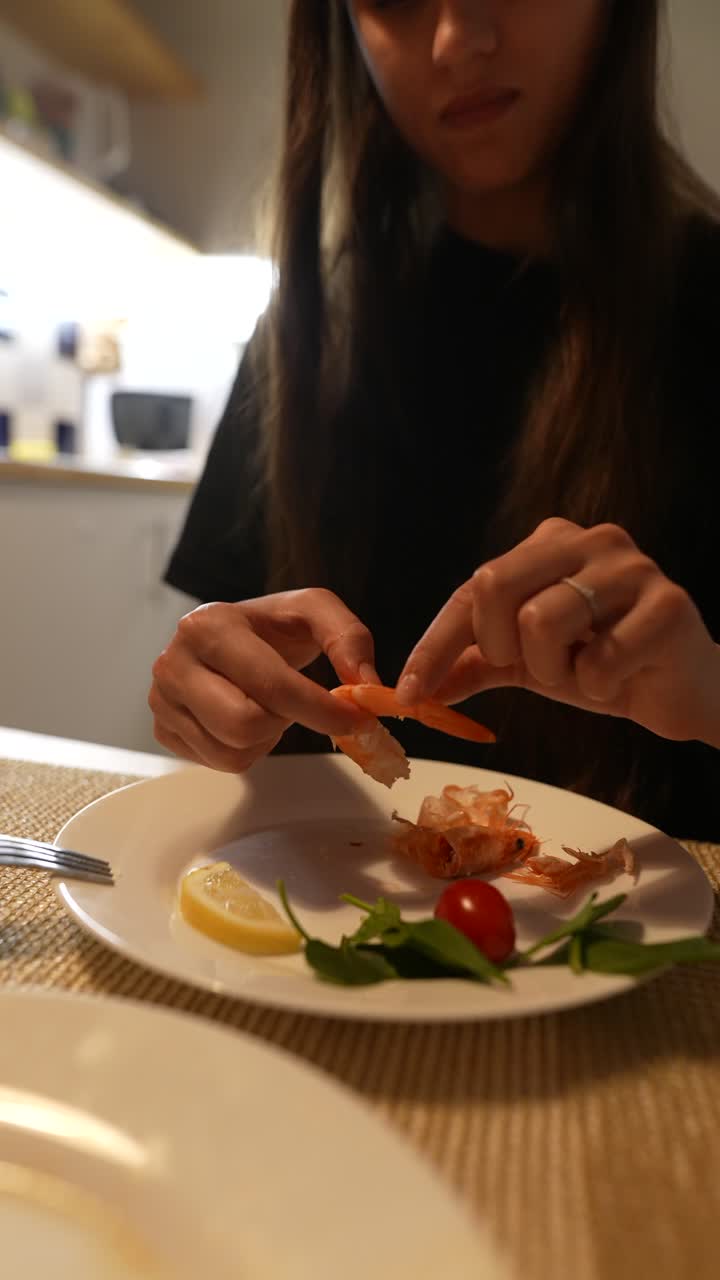 una mujer comiendo camarones en casa.