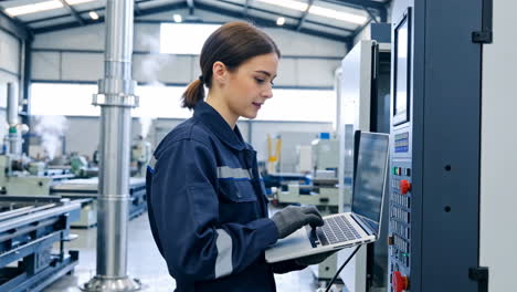 female engineer operating industrial machinery with a laptop
