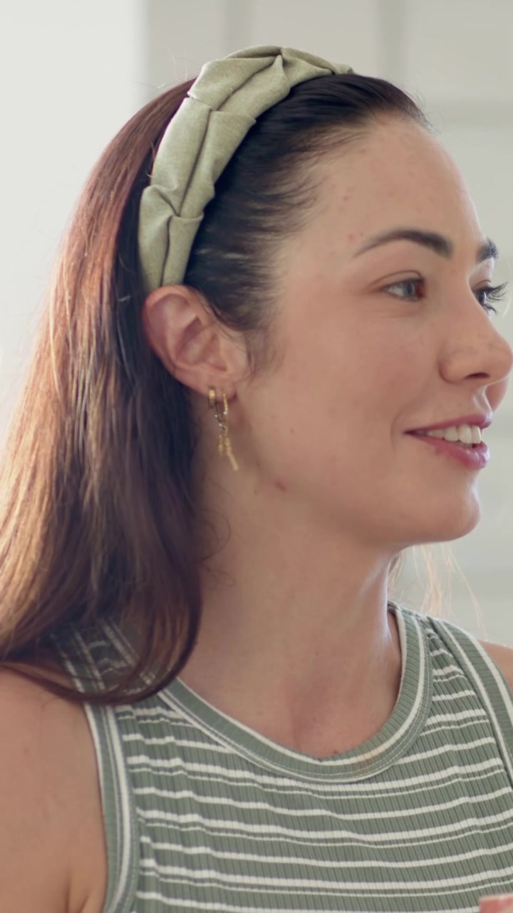 Video verticale: La telecamera mostra una donna che gira la testa e parla in cucina vicino alla finestra, con una fascia per capelli.