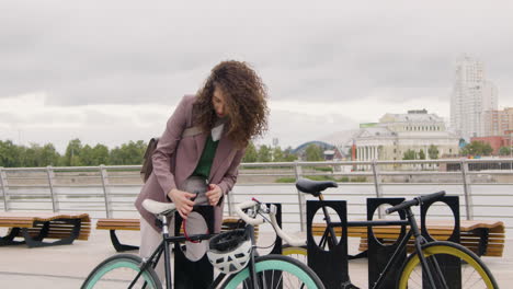 Hübsche-Frau-In-Formeller-Kleidung,-Die-Ihr-Fahrrad-Auf-Der-Stadtbrücke-Parkt,-Während-Sie-Zur-Arbeit-Geht