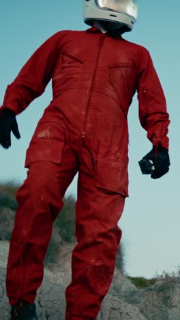 astronauta con traje naranja y casco camina sobre las rocas de un planeta hostil
