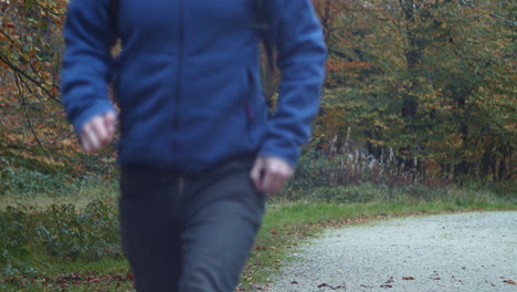 man with backpack runs past camera along autumn trail, slow motion