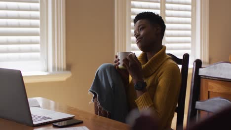 african american woman drinking coffee while working from home