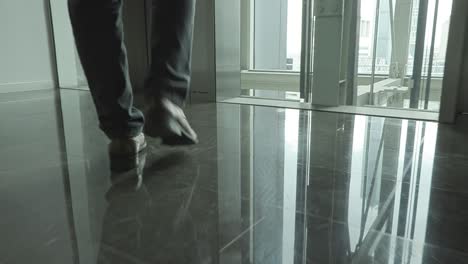 view of man in suits is holding briefcase and walking along hallway, slow motion