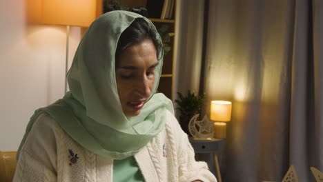 woman wearing hijab at muslim family table at home eating iftar meal breaking daily fast during ramadan