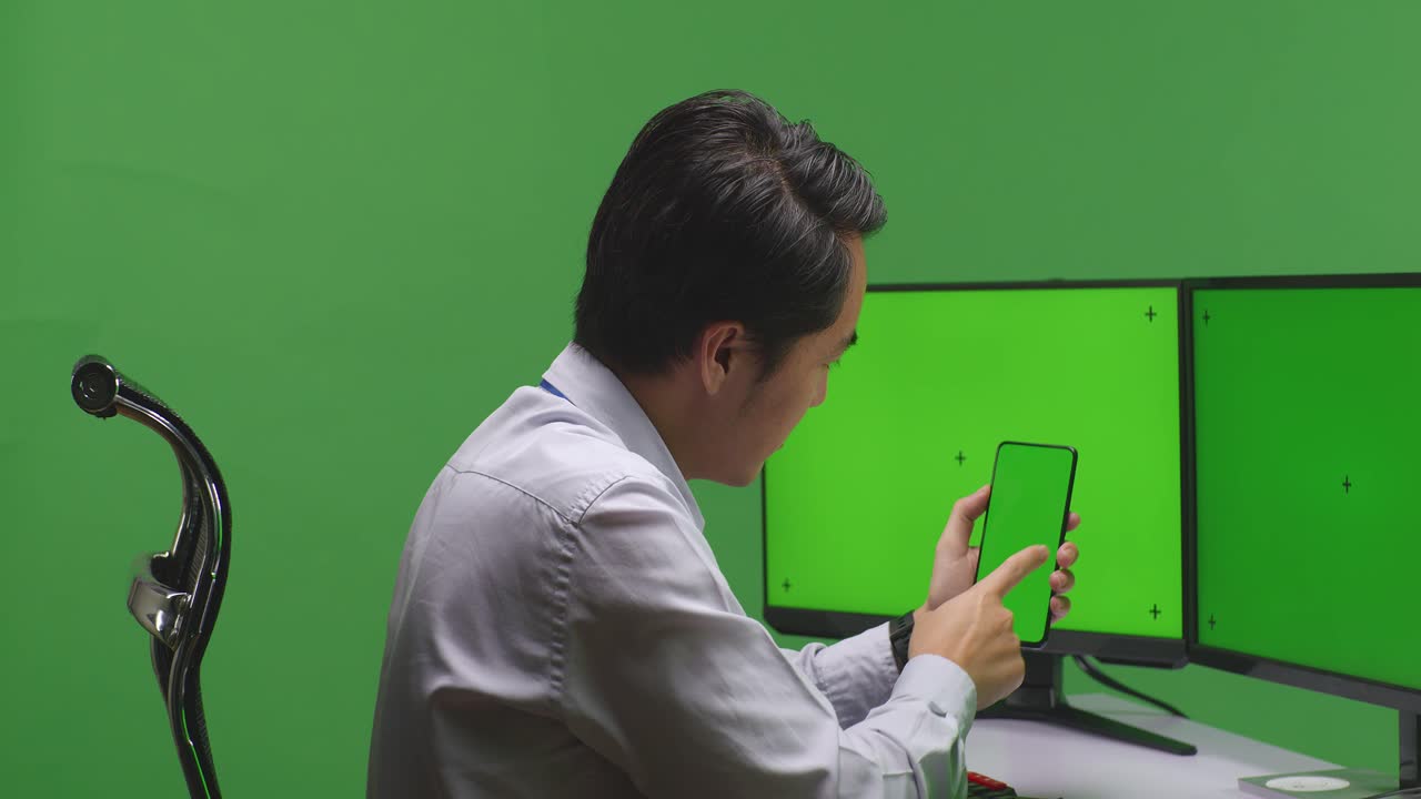 휴대전화와 여러 모니터를 사용하는 사업가