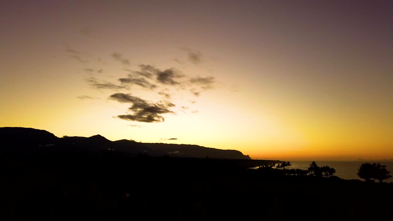 HD Timelapse Hawaii Kauai clouds dissipate over rocky cliffs near sunset with sky changing from blue to purple from day to night with ocean in distance