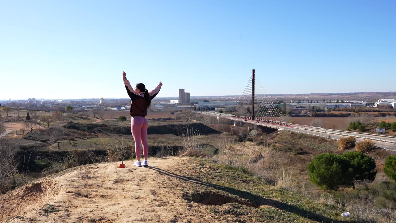 una mujer celebra haber llegado a la cima de la montaña durante su entrenamiento de carrera