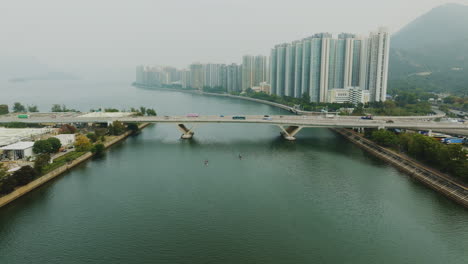 drone descending towards a bridge over a large river during a gloomy grey day