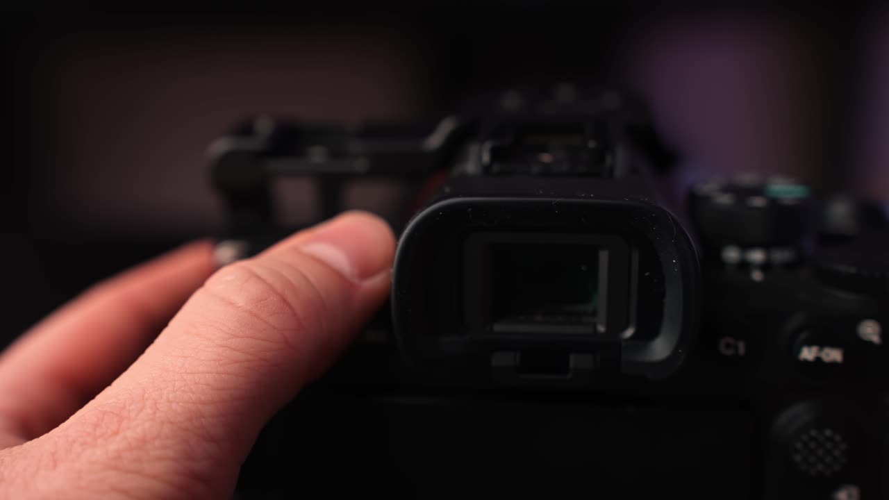 Slow rotation close-up of mirrorless camera electronic viewfinder and top controls, with hand support and soft studio bokeh for cinematic creator gear footage