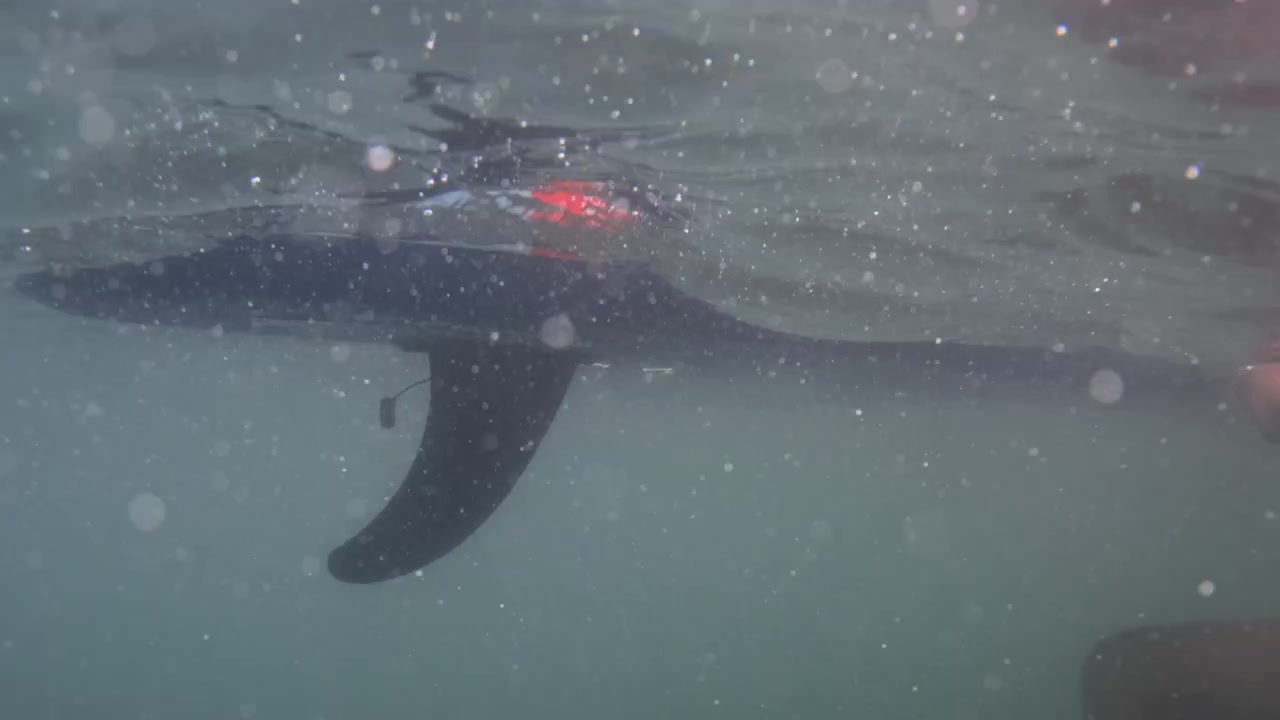 Person paddling a kayak underwater in murky water, with air bubbles rising, creating a sense of adventure and motion