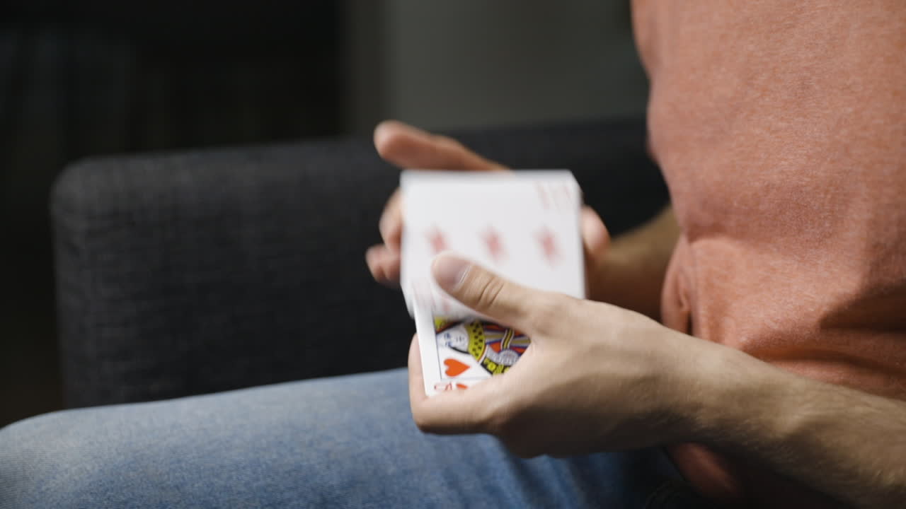 Long shot from side of male hands shuffling and dropping playing cards