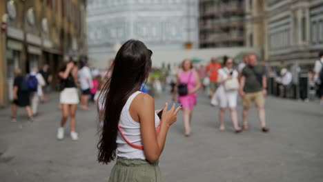 mujer tomando fotos en una calle concurrida de la ciudad