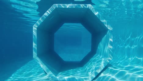 captivating underwater perspectives: a glimpse through an octagonal structure in a crystal clear pool, showcasing light reflections and serene aquatic ambiance