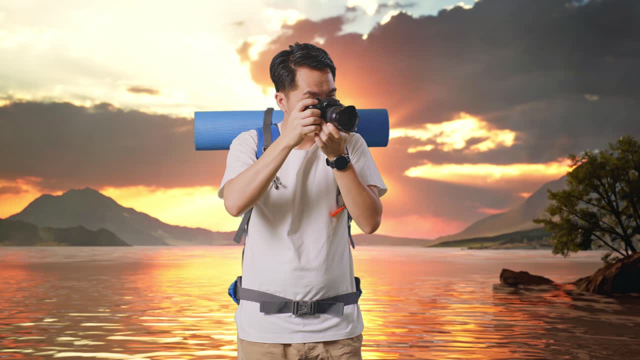 excursionista masculino asiático con mochila de montañismo usando una cámara tomando fotos en un lago