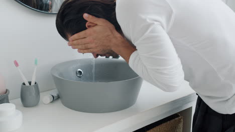 hombre lavándose la cara en el baño