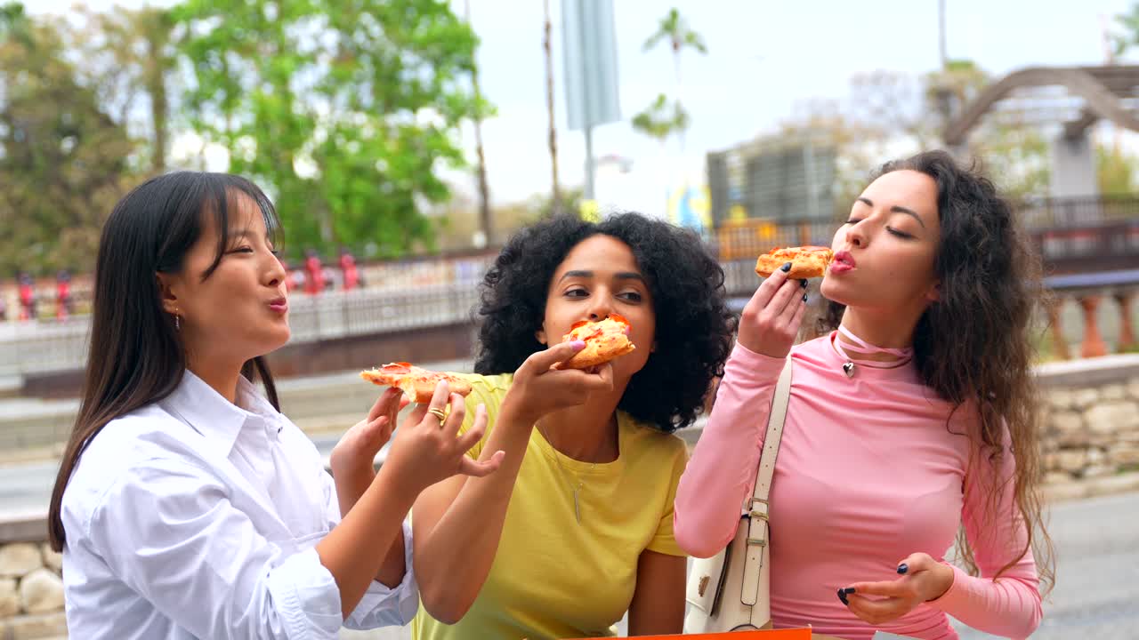 Three friends enjoying pizza together outdoors