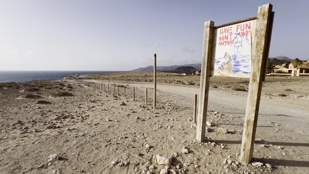 Have Fun Don't Judge Anyone' sign on a desolate coastal roadside in Fuerteventura, Spain. Concept of positivity, freedom, and non-judgment