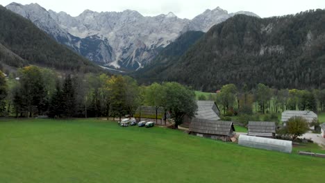 drone flying away from campervans as it shows more of the mountains and farms in the background. jezesko valley in slovenia in autumn season aerial view