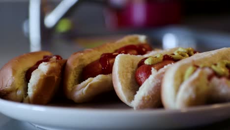 close up rotating shot of a plate of hotdogs with ketchup and mustard