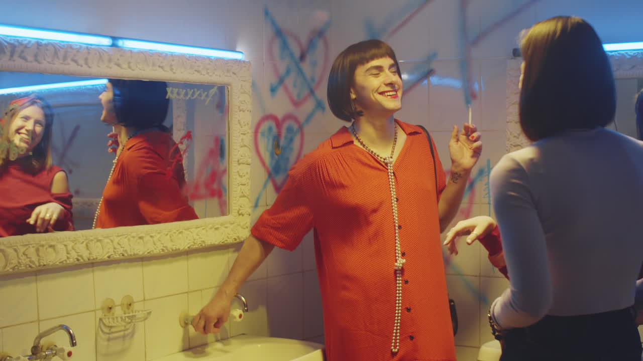 쾌활한 트랜스젠더 남자가 담배를 피우고 여자친구와 채팅하고 있습니다.