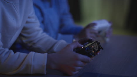 Nahaufnahme-Von-Zwei-Kleinen-Jungen-Zu-Hause,-Die-Spät-In-Der-Nacht-Mit-Einer-Computerspielkonsole-Am-Fernseher-Spielen-Und-Controller-In-Der-Hand-Halten-2