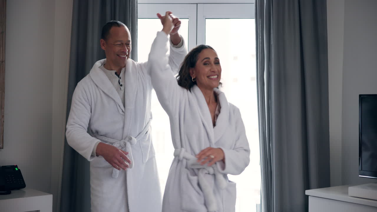 Couple dancing in bathrobes in a hotel room