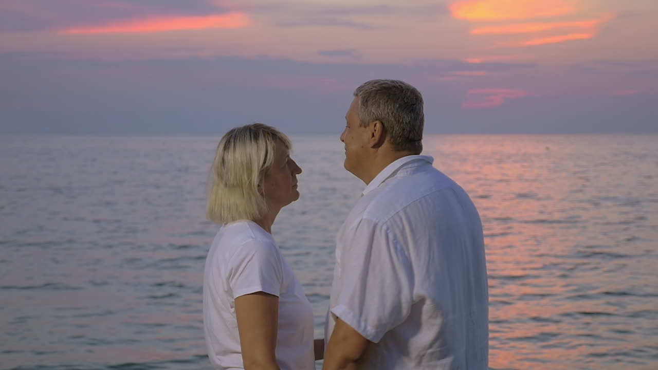 해가 지는 바다에서 미소 짓는 노인 부부