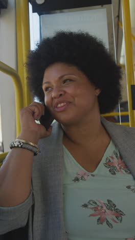 vertical video of happy plus size biracial woman using smartphone in bus