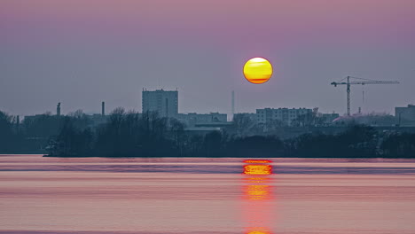 A-golden-sunset-reflecting-off-the-ocean-water-along-a-city-shoreline---time-lapse