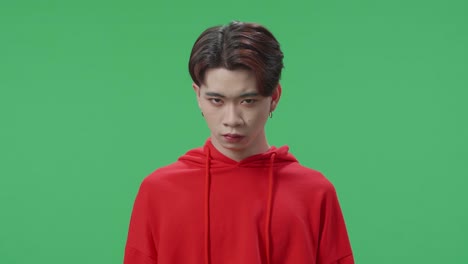 terrible asian transgender male looking at camera in the green screen studio
