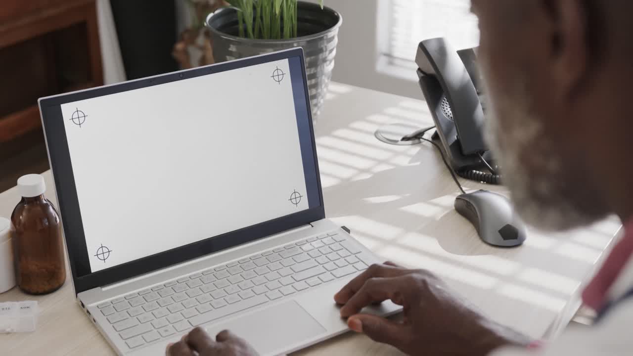 médico afroamericano sentado en un escritorio y usando una computadora portátil con espacio para copiar, cámara lenta