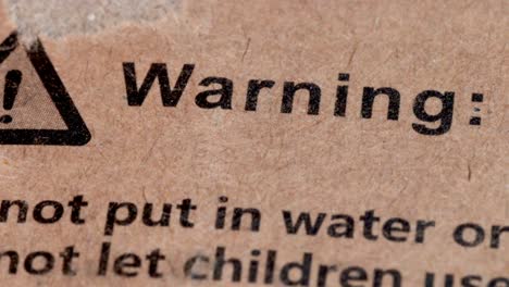 warning sign on the cardboard surface of a box, waning text in the paperboard of the box of a product macro shot in close up view