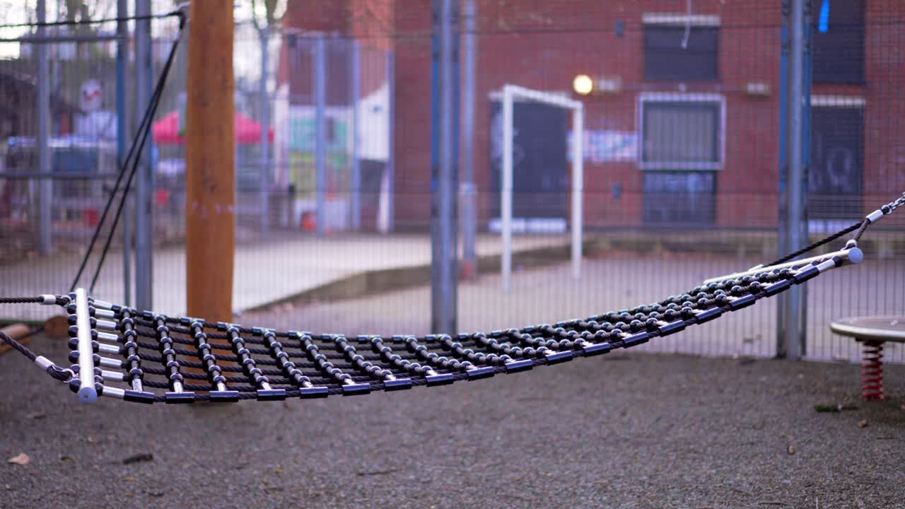 детская площадка во время пандемии коронавируса ковид-19, пустые декорации во время блокировки, качающийся хамак в замедленном режиме, футбольный корт на заднем плане