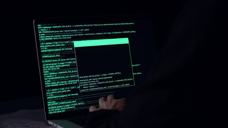 Hackerens hænder bruger bærbar computer til at hacke i et mørkt rum